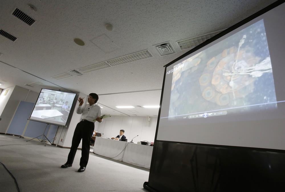 Tokyo Electric Power Co. (TEPCO) spokesman Takahiro Kimoto speaks during a press conference while showing video image taken by an underwater robot into Fukushima nuclear plant to search for melted fuel, at the TEPCO headquarters in Tokyo Wednesday, July 19, 2017. The underwater robot captured images and other data inside Japan's crippled Fukushima nuclear plant on its first day of work. The robot is on a mission to study damage and find fuel that experts say has melted and mostly fallen to the bottom of a chamber and has been submerged by highly radioactive water. (AP Photo/Eugene Hoshiko)